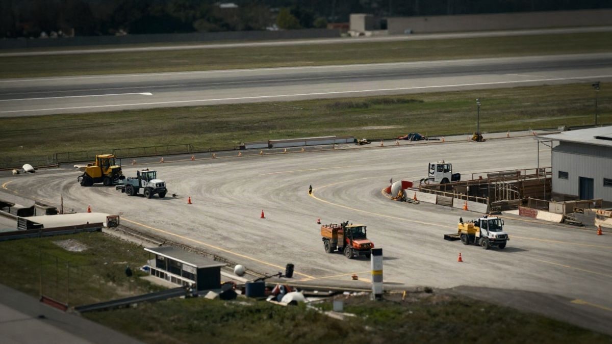 Imagen ilustrativa: vista cenital de una pista de aeropuerto en obras con vehículos y conos de señalización