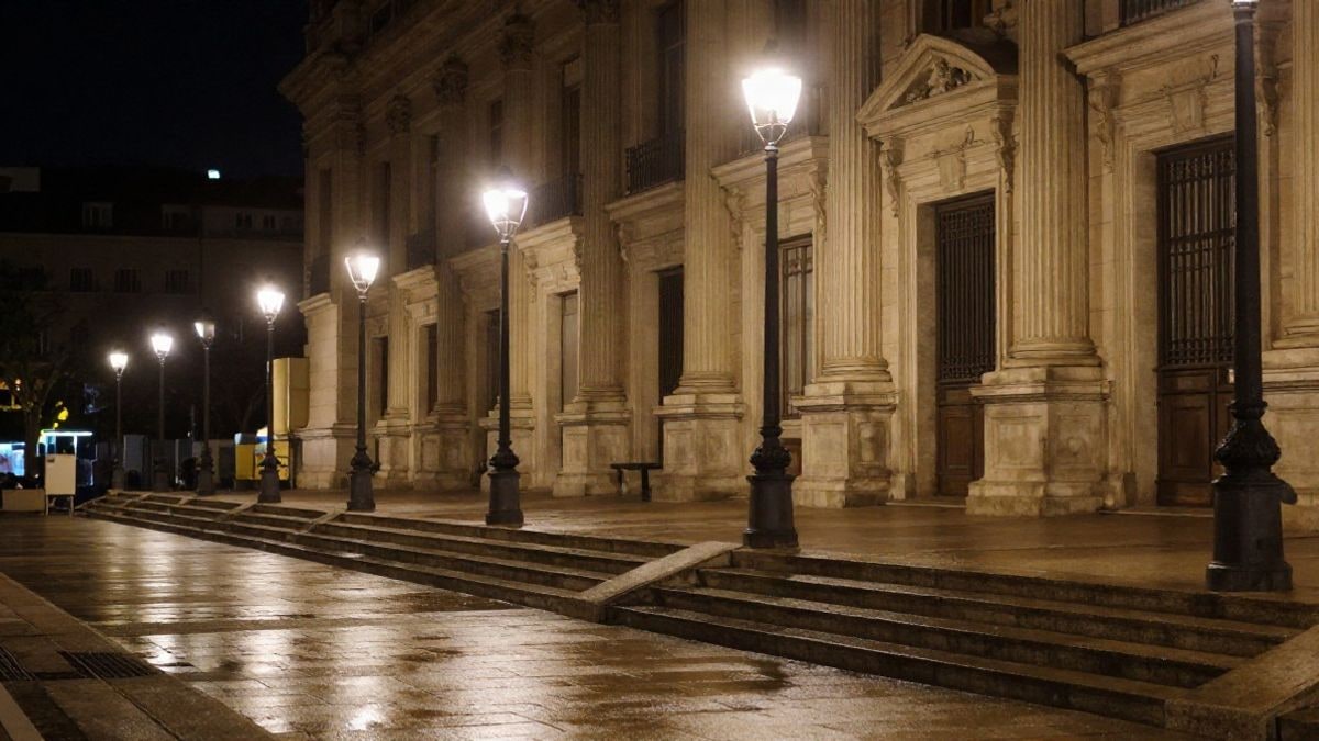 Illustrative image: facade of a stone institutional building lit by street lamps at night