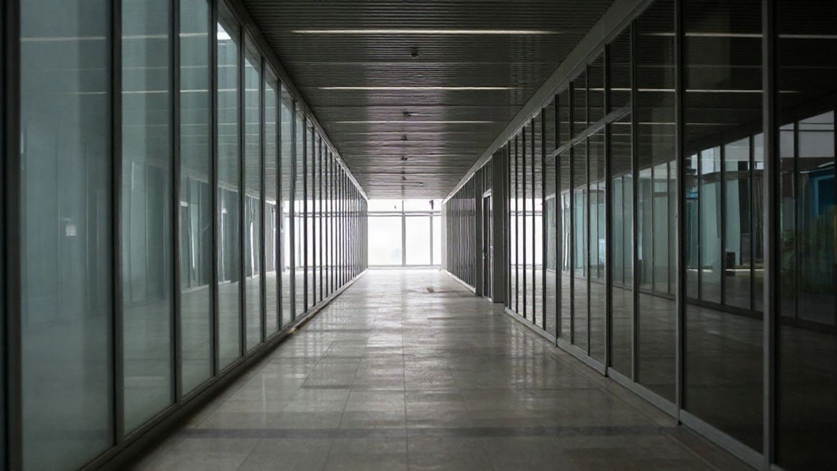 Imagen ilustrativa: un pasillo acristalado de oficinas modernas con líneas que convergen al fondo, iluminado por luz natural