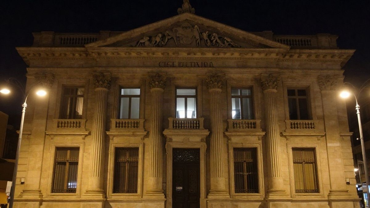 Imagen ilustrativa: fachada de un edificio institucional iluminada de noche con farolas