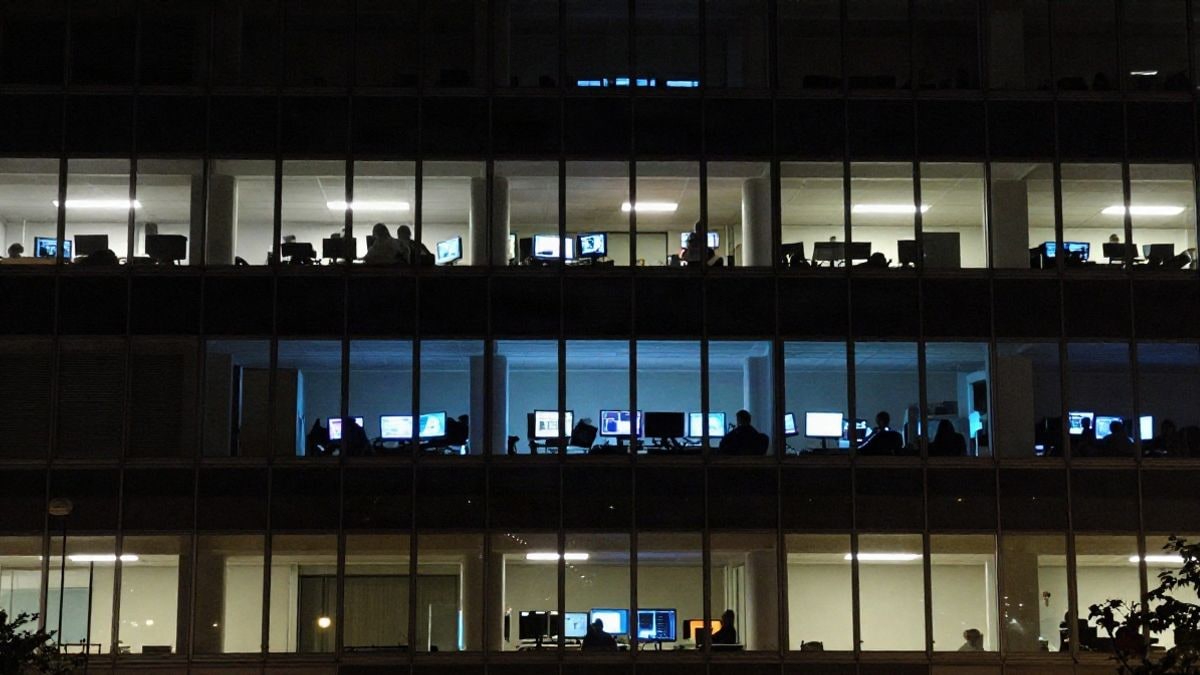 Imagen ilustrativa: edificio de oficinas de noche con luces encendidas y pantallas de un centro de seguridad