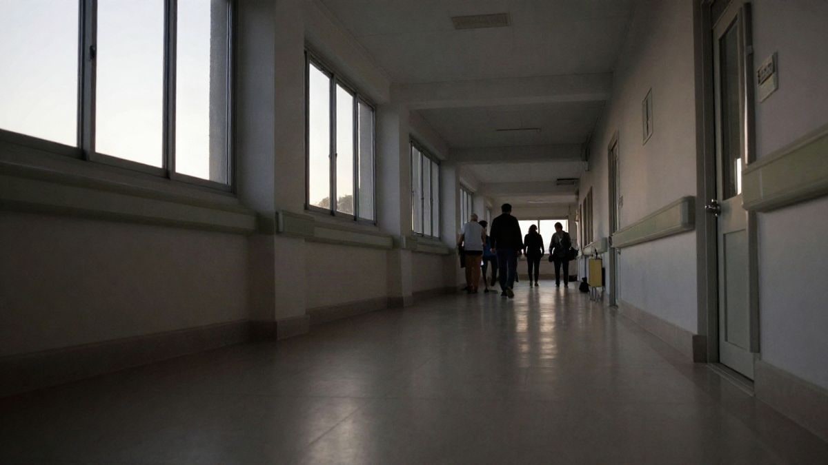 Imagen ilustrativa: pasillo de hospital vacío con silla de ruedas y luz natural al amanecer