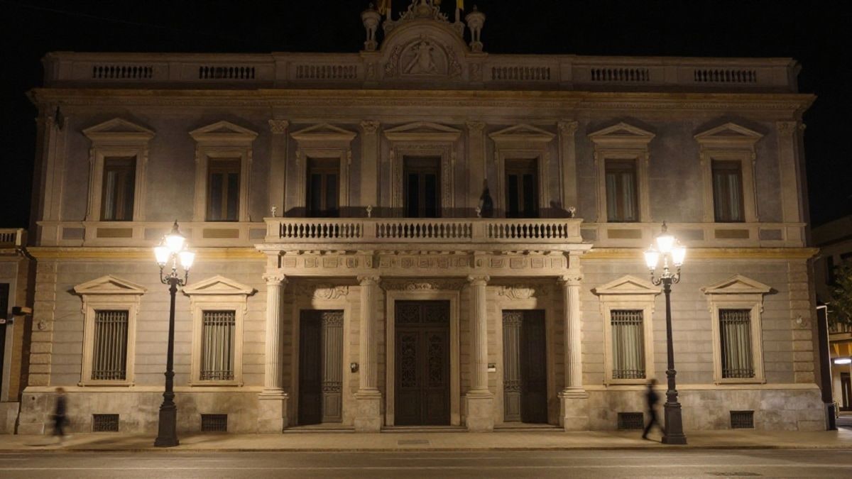 Illustrative image: facade of an institutional building illuminated by streetlights at night