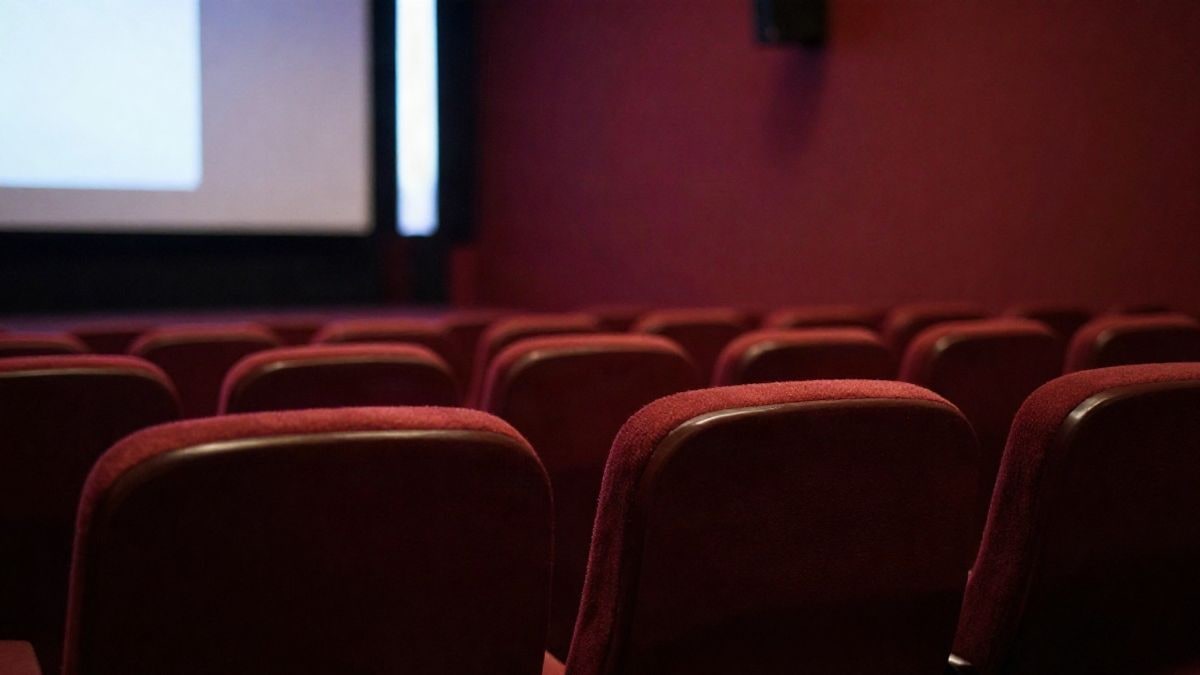 Illustrative image: a row of empty seats in an old cinema with a blurred screen in the background