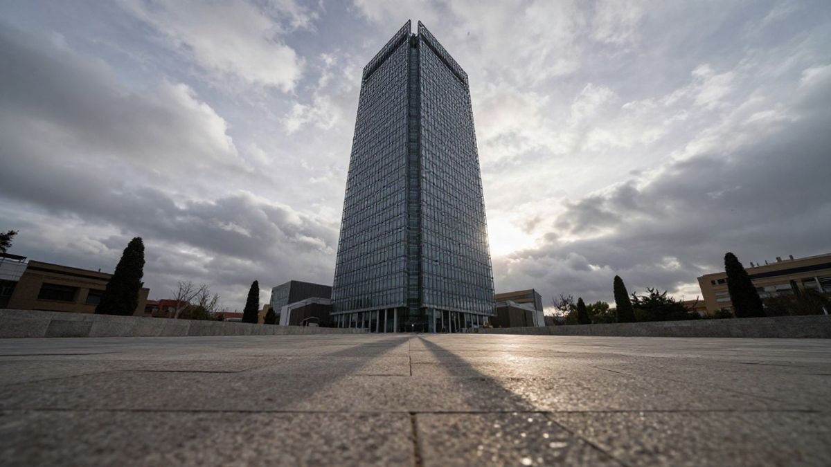Illustrative image: glass office tower viewed from below against a cloudy sky at sunset
