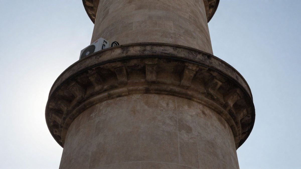 Imagen ilustrativa: torre de telecomunicaciones con equipos de climatización en su base, vista en ángulo bajo