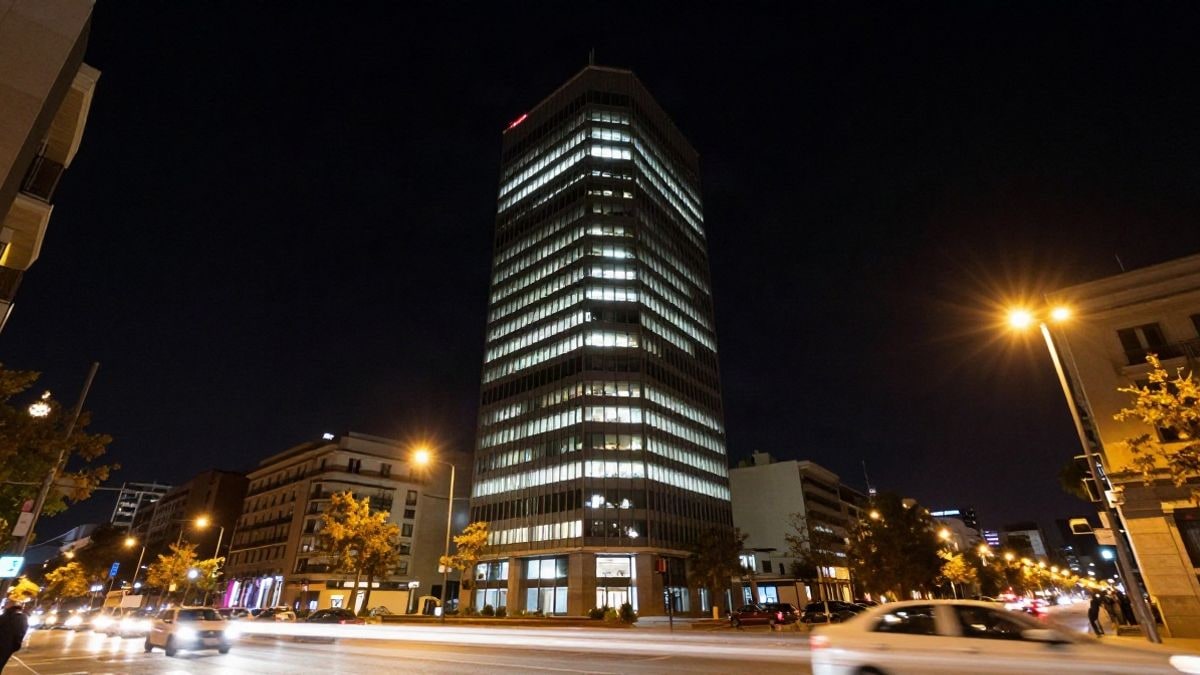 Illustrative image: a modern office building lit up at night, with blurred traffic lights in the foreground