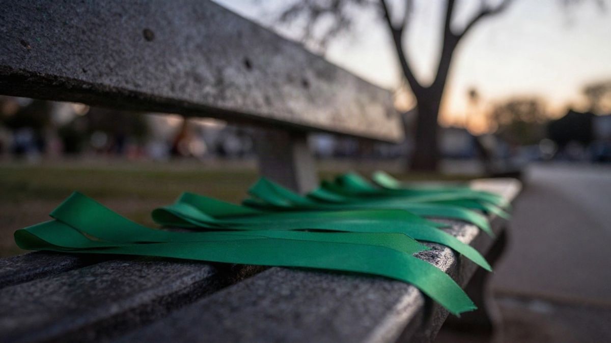Illustrative image: green ribbons folded on a stone bench in a park at dawn, with a blurred background