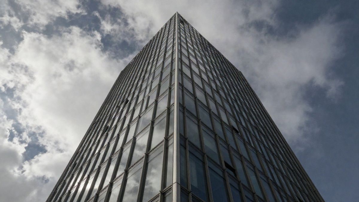 Imagen ilustrativa: torre de oficinas de cristal vista desde abajo contra un cielo dramático al atardecer