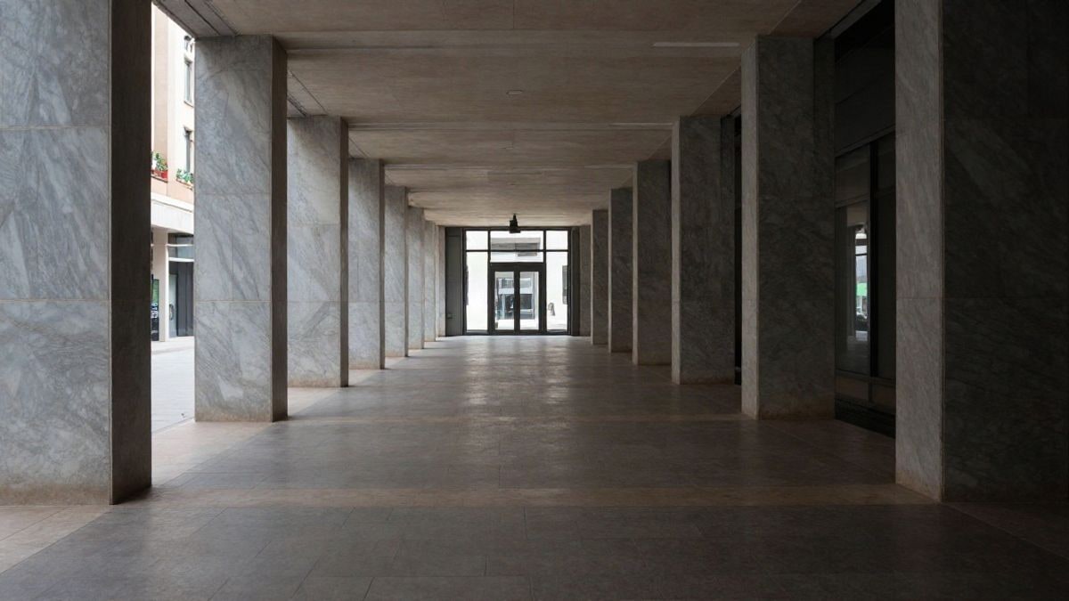 Illustrative image: a long, empty corridor of an office building with natural light in the background
