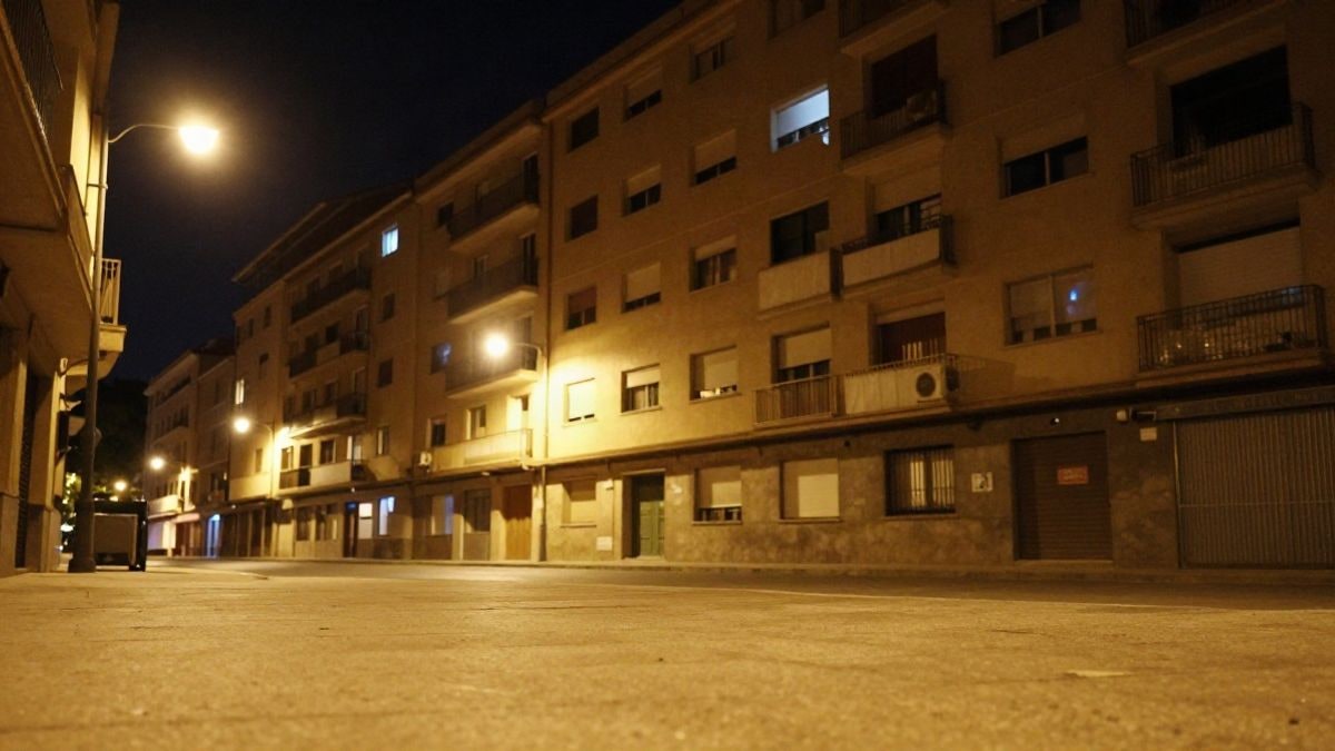Imagen ilustrativa: bloque de viviendas residenciales iluminado por farolas en una calle nocturna.