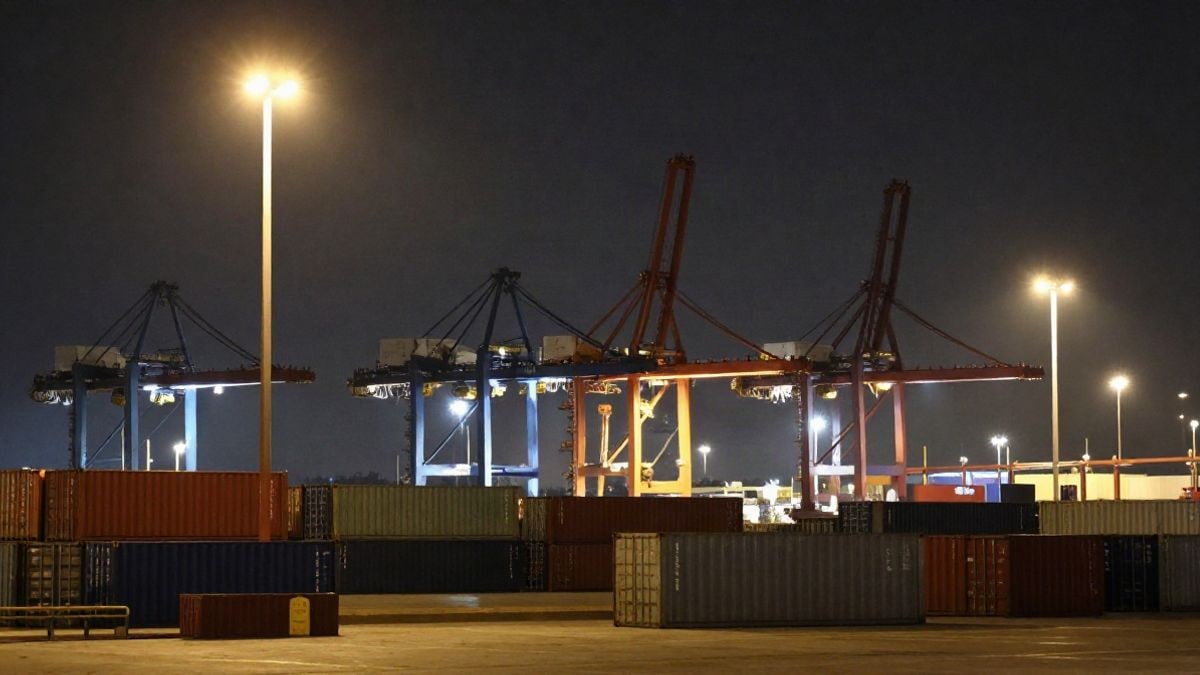 Imagen ilustrativa: grúas de un puerto de contenedores iluminadas de noche junto al muelle