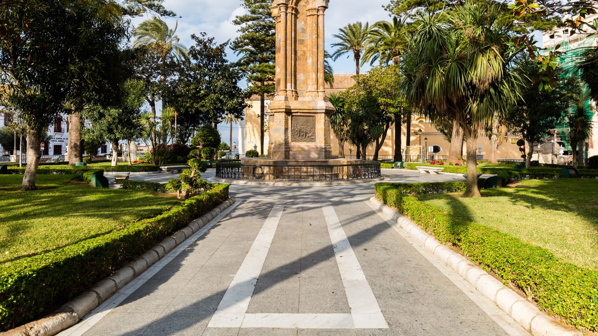 Plaza de África de Ceuta con monumento gótico, palmeras y jardines cuidados a la luz de la mañana
